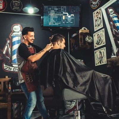 smiling-man-cutting-another-mans-hair-inside-shop-2061820